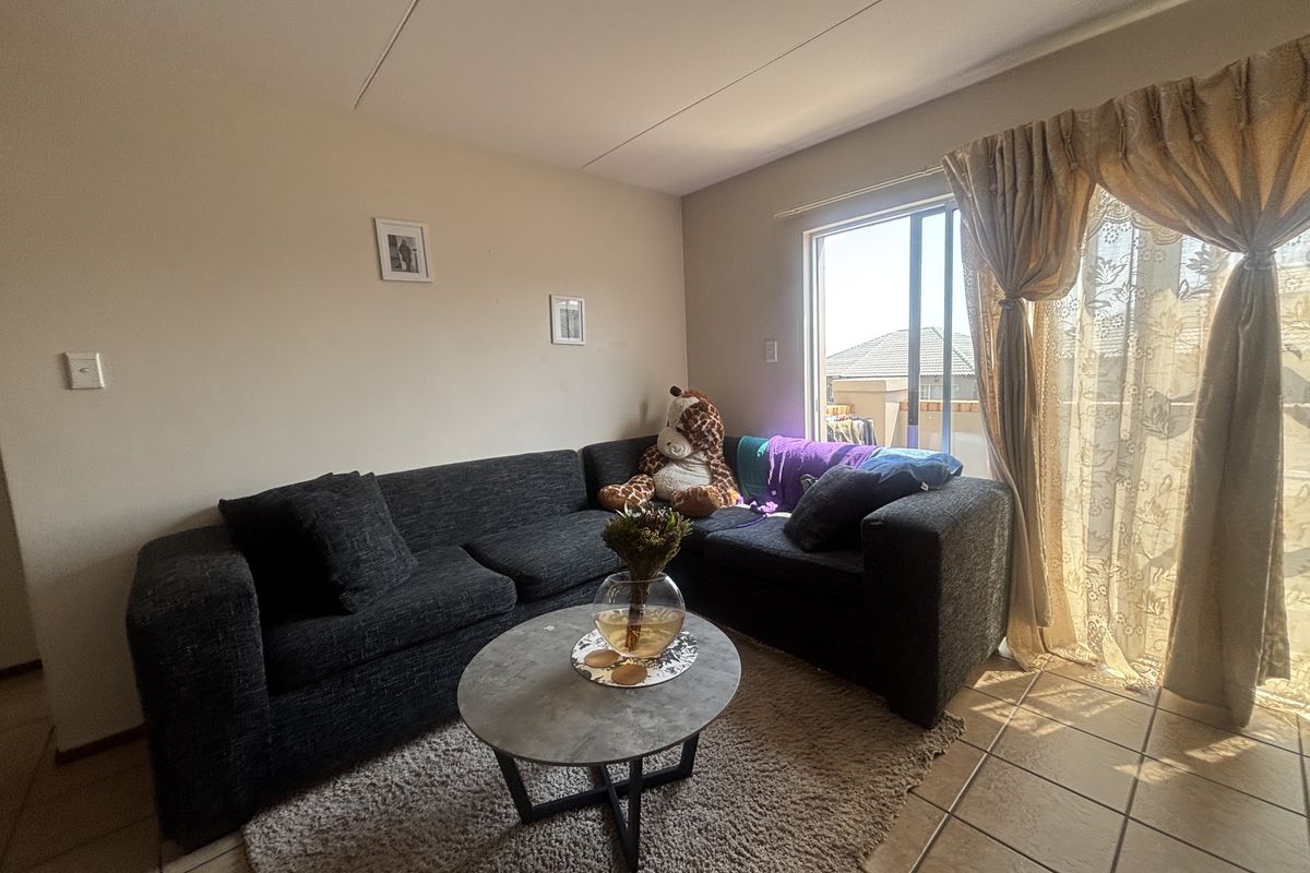 A living room featuring tiled flooring and a sliding glass door providing natural light and access to the exterior.