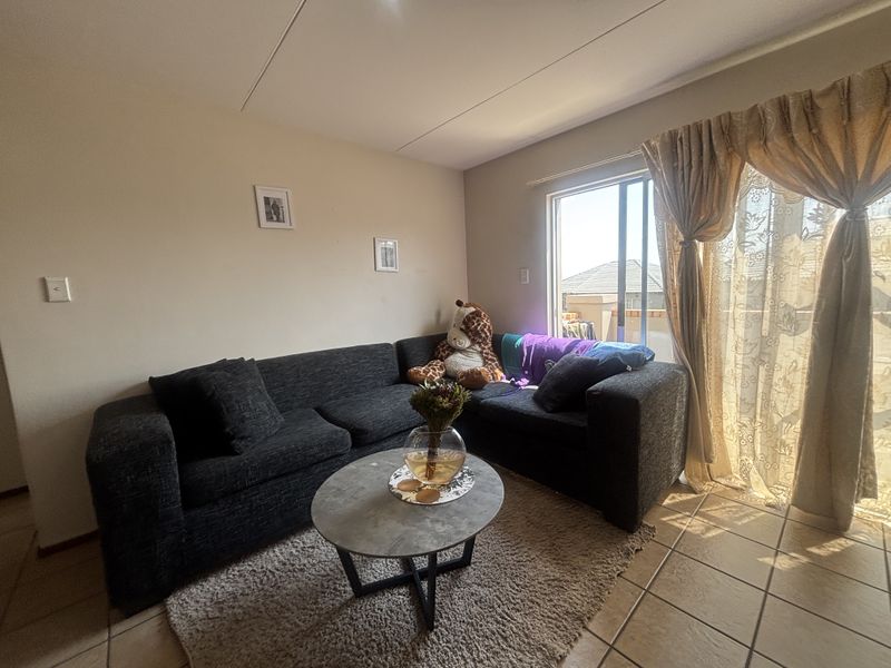 A living room featuring tiled flooring and a sliding glass door providing natural light and access to the exterior.