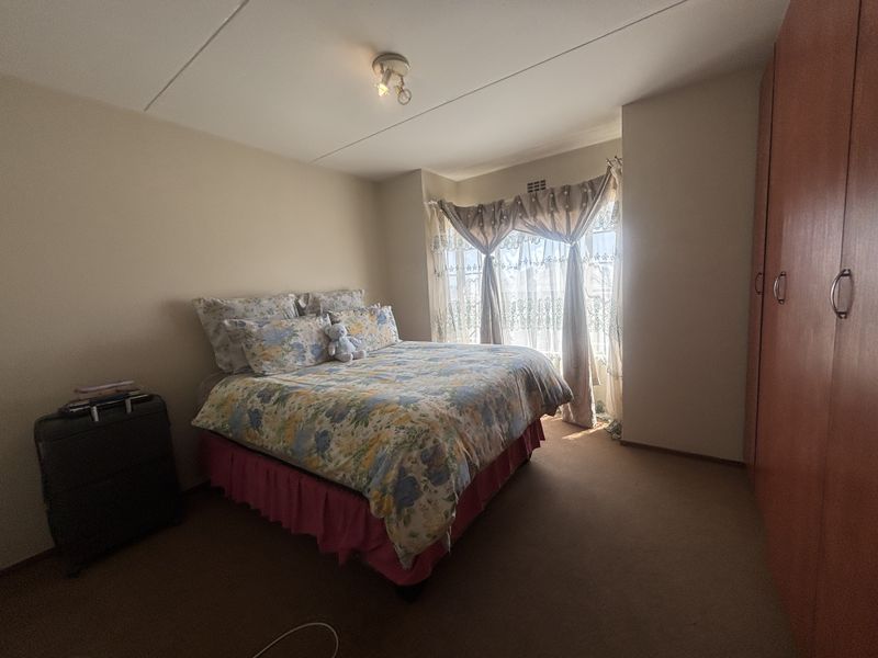 A bedroom featuring built-in cupboards, carpeted flooring, and a bay window that allows for natural light.