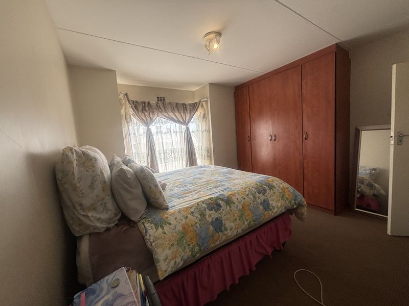 A bedroom featuring built-in wooden cupboards and a window with natural light.