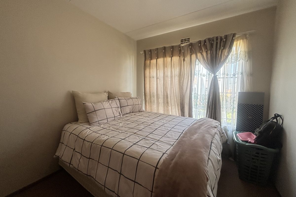 A standard bedroom featuring neutral walls, carpeted flooring, and a sliding glass door providing natural light.