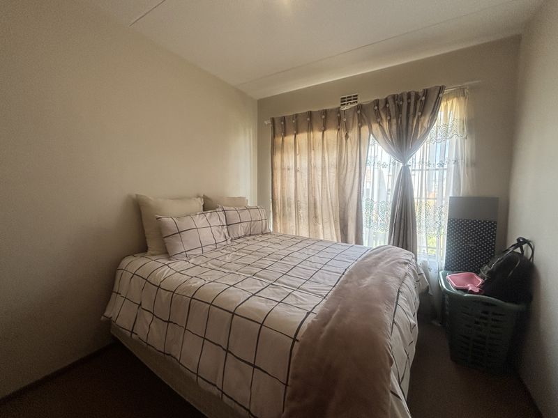 A standard bedroom featuring neutral walls, carpeted flooring, and a sliding glass door providing natural light.