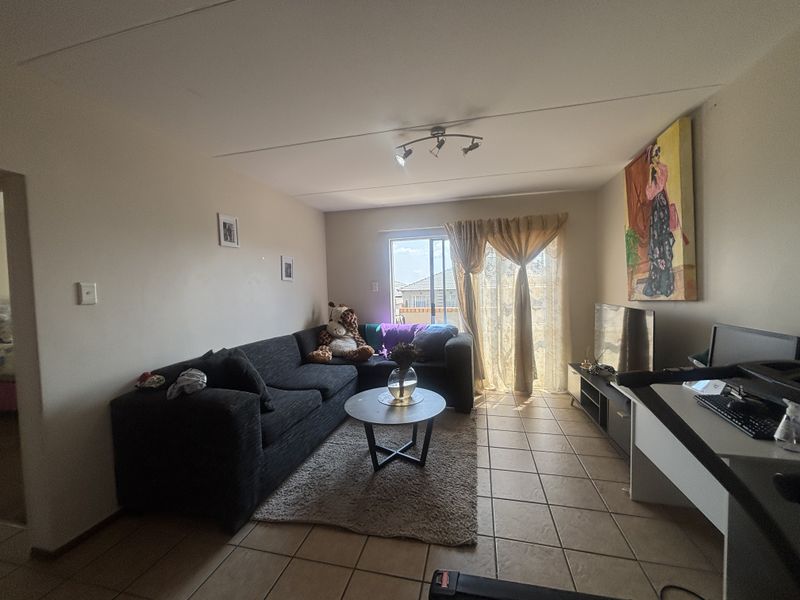 A living room featuring tiled flooring, track lighting, and a sliding glass door providing natural light and access to the exterior.