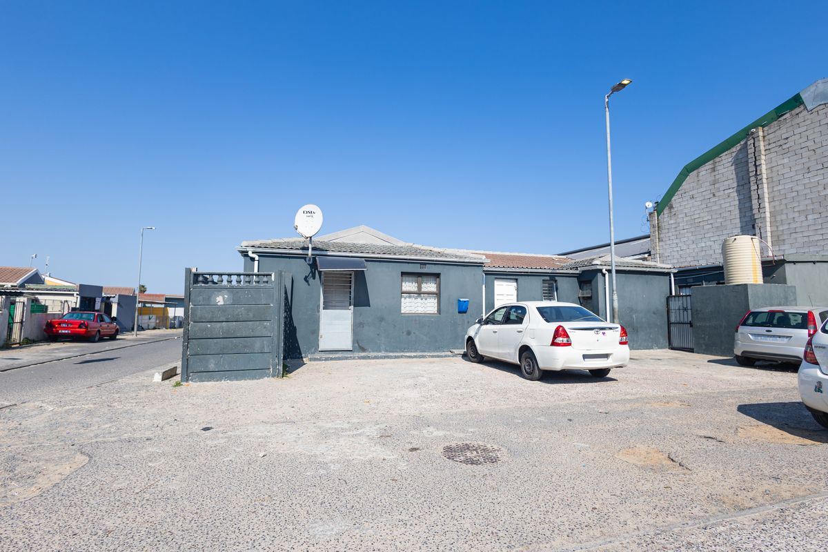 Front exterior view of a single-story residential property featuring a paved driveway, security gate, and satellite dish installation.