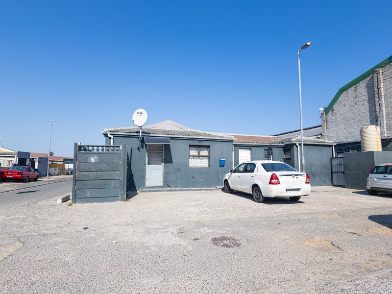 Front exterior view of a single-story residential property featuring a paved driveway, security gate, and satellite dish installation.