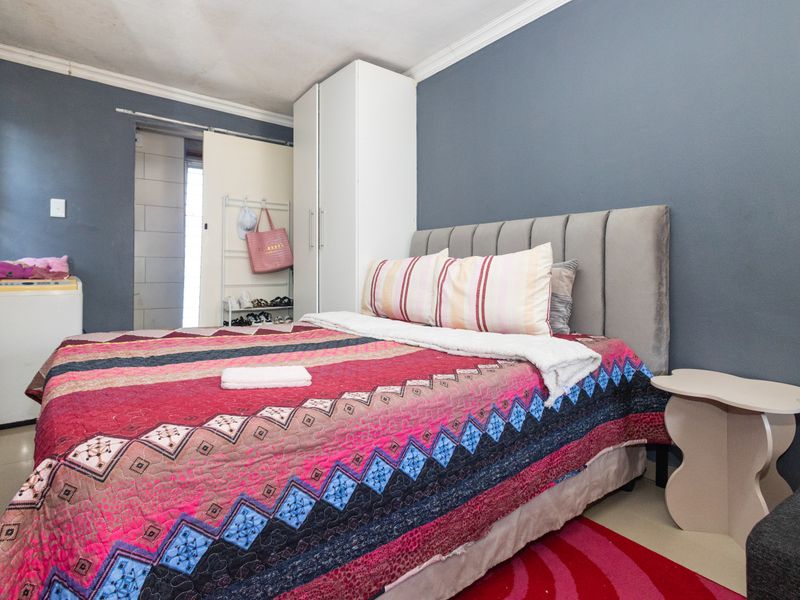 A bedroom featuring tiled flooring, a built-in wardrobe, and direct access to an adjacent bathroom area.