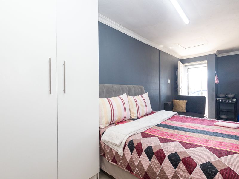 A bedroom featuring a built-in wardrobe, dark blue accent wall, and direct access to an exterior doorway.