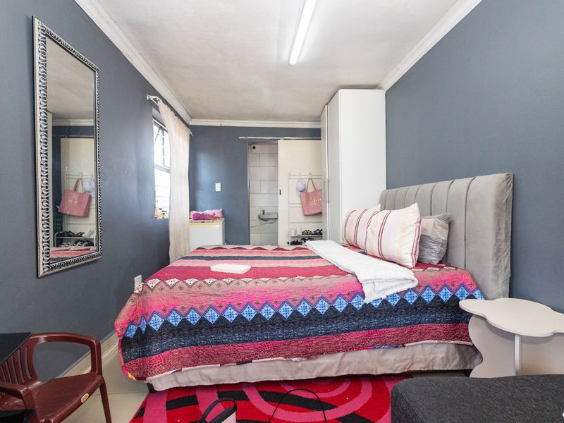 A bedroom featuring dark grey walls, built-in wardrobe storage, and direct access to an en-suite bathroom area.