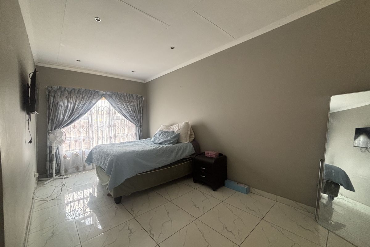 A bedroom featuring tiled flooring, recessed downlighting, and a security gate over the window.