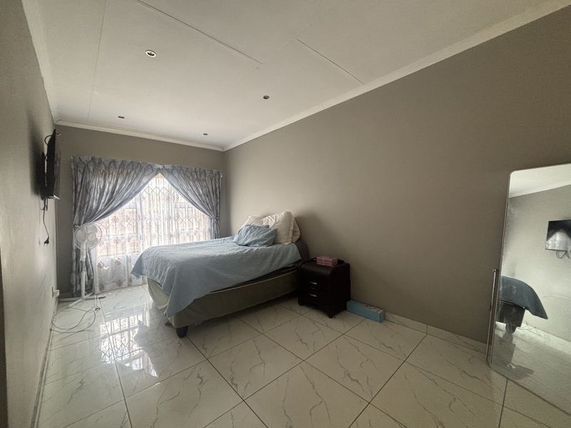 A bedroom featuring tiled flooring, recessed downlighting, and a security gate over the window.