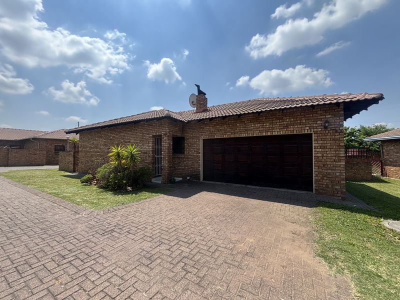 Front view of a face brick house featuring a tiled roof, paved driveway, and an integrated double garage.