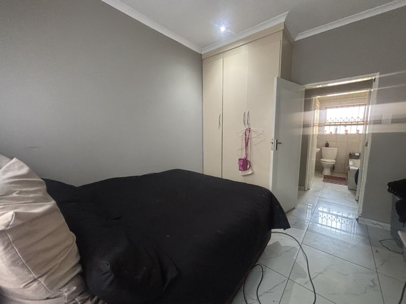 A bedroom featuring built-in cupboards, tiled flooring, and direct access to an en-suite bathroom.
