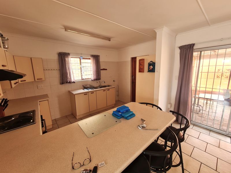 Open-plan kitchen and dining area featuring built-in cabinetry, tiled flooring, and direct access to an outdoor patio through sliding glass doors.