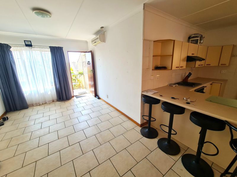 Open-plan living and kitchen area featuring tiled flooring, built-in cabinetry, a breakfast counter, and direct access to an outdoor space.