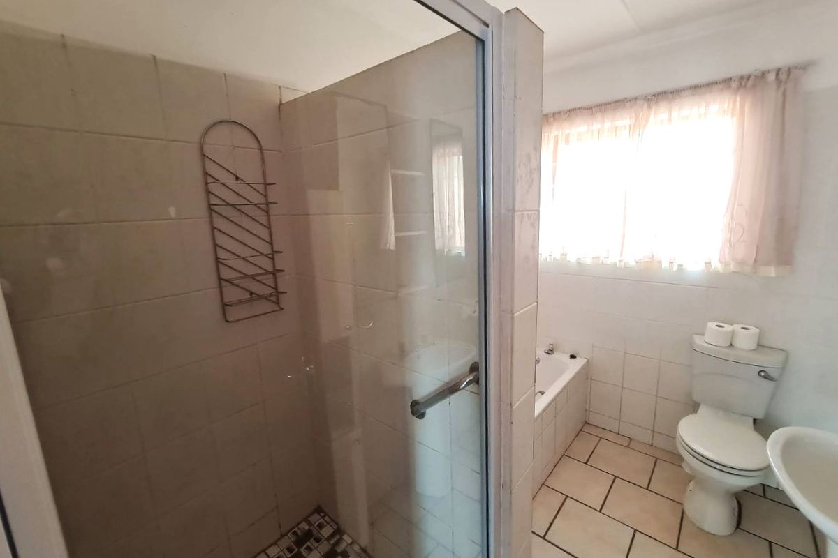 Functional bathroom featuring a separate shower enclosure, bathtub, pedestal sink, and toilet with neutral wall and floor tiling.