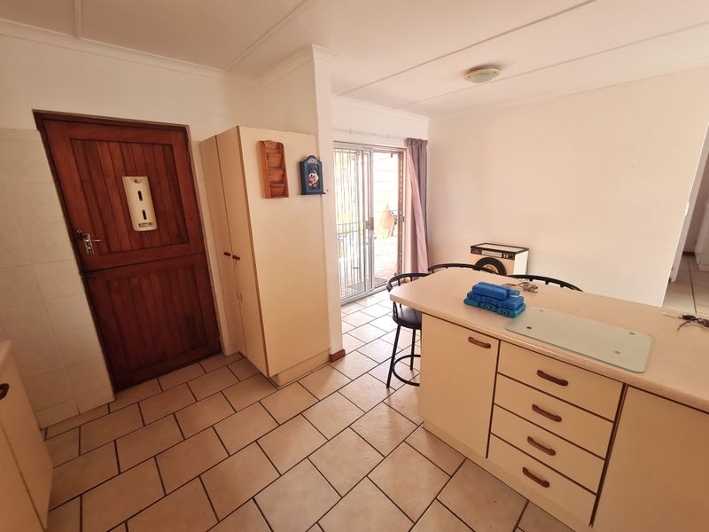 A functional kitchen area featuring a central island, tiled flooring, and direct access to an outdoor patio through a sliding glass door.