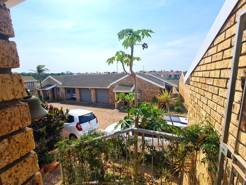 Elevated view of a townhouse complex featuring face brick exteriors, tiled roofs, and a paved driveway with garage access.
