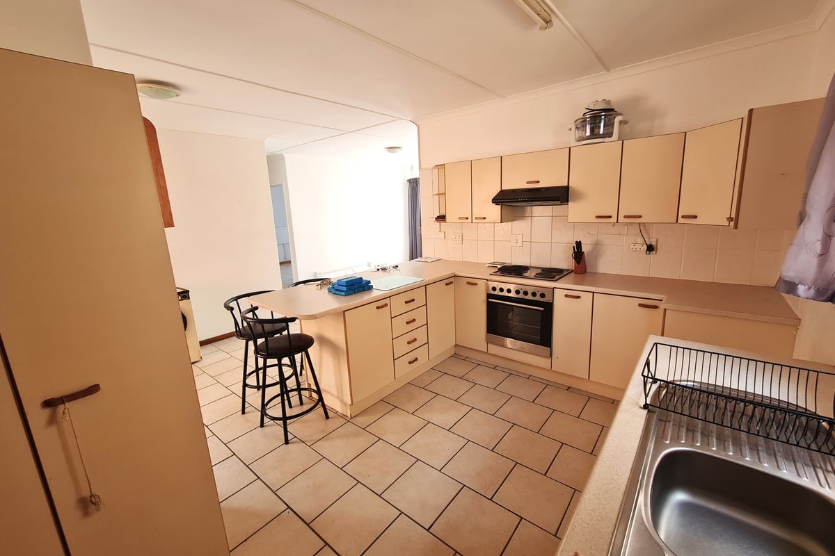 A functional kitchen featuring built-in cabinetry, a breakfast bar, tiled flooring, and integrated cooking appliances, offering a practical layout with potential for modern updates.