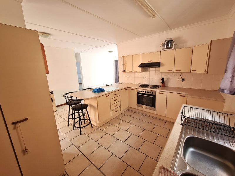 A functional kitchen featuring built-in cabinetry, a breakfast bar, tiled flooring, and integrated cooking appliances, offering a practical layout with potential for modern updates.