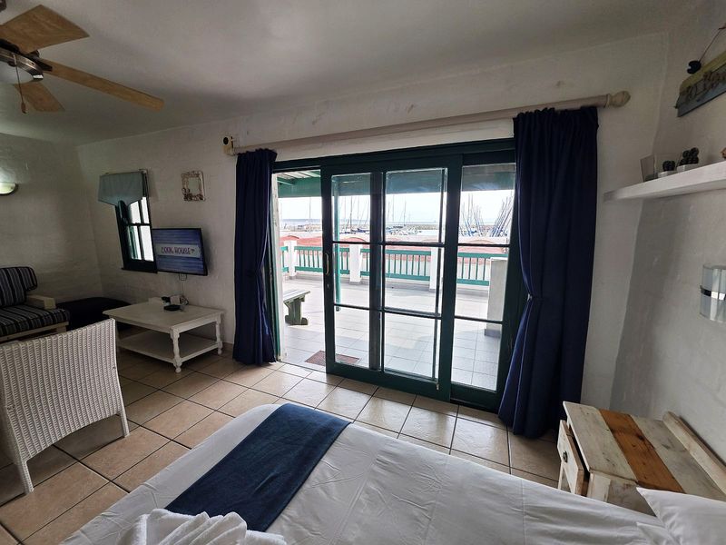 Bedroom featuring tiled flooring, a ceiling fan, and large sliding glass doors providing access to a balcony with marina views.