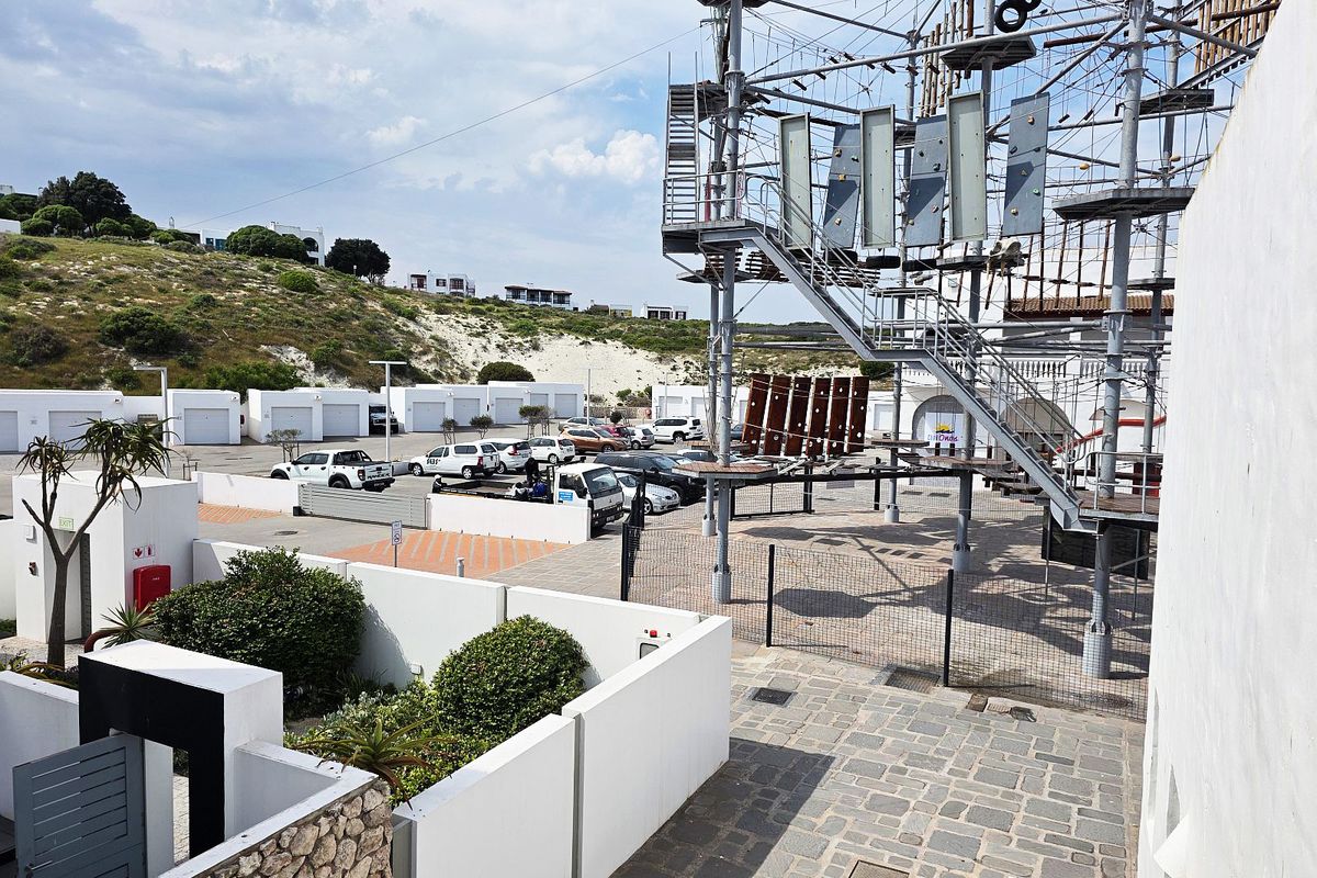 Exterior view of a paved courtyard area featuring a large climbing structure and perimeter walling within an apartment complex setting.