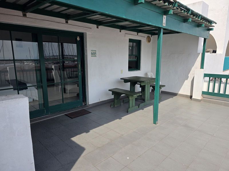 A covered patio area featuring tiled flooring and a sliding glass door entrance, providing a functional outdoor space for the apartment.