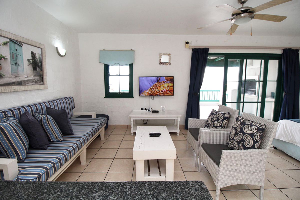 A bright living room featuring tiled flooring, a ceiling fan, and sliding glass doors that provide access to an outdoor patio area.
