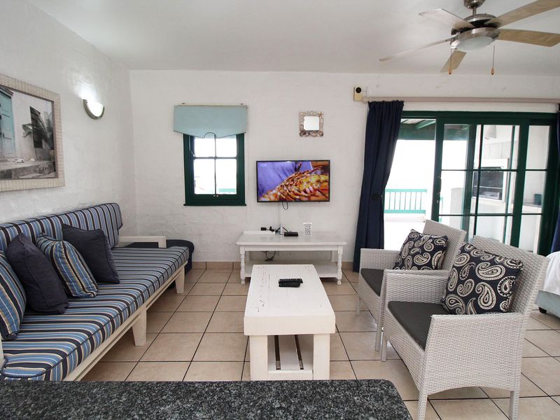 A bright living room featuring tiled flooring, a ceiling fan, and sliding glass doors that provide access to an outdoor patio area.