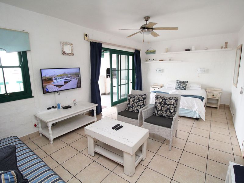 Open-plan studio apartment featuring tiled flooring, a ceiling fan, and direct access to a private balcony through sliding glass doors.