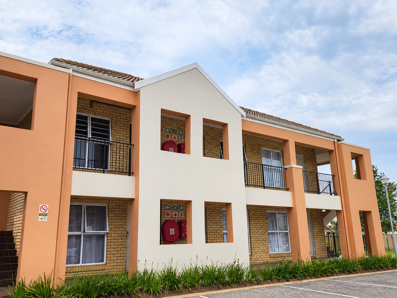 A well-maintained multi-story apartment building featuring a brick and plaster facade, external staircases, and integrated fire safety equipment.