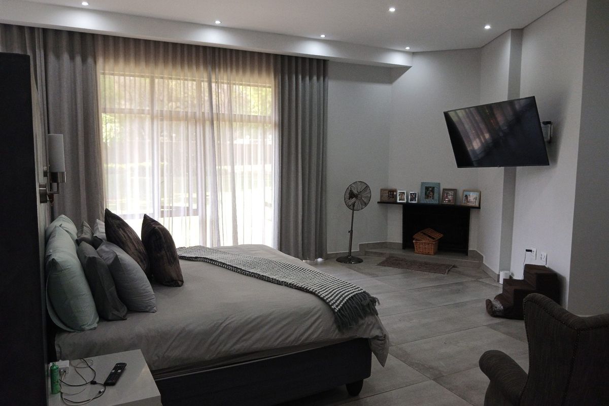 Spacious bedroom featuring large windows with floor-to-ceiling curtains, tiled flooring, and recessed ceiling lighting.