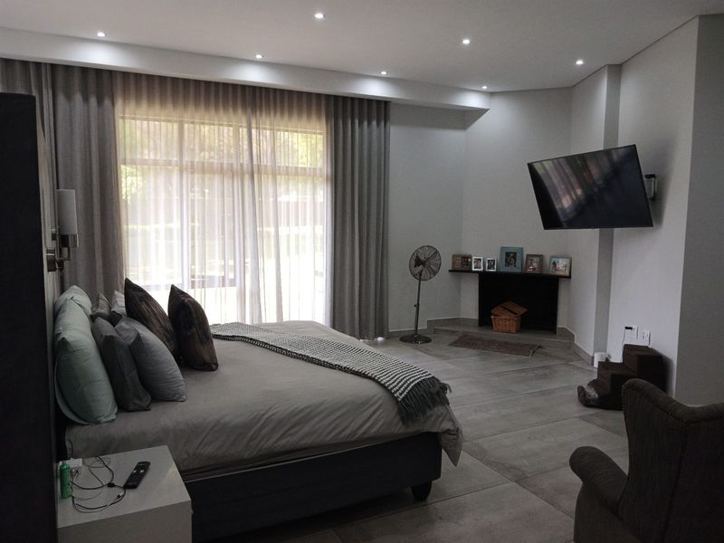 Spacious bedroom featuring large windows with floor-to-ceiling curtains, tiled flooring, and recessed ceiling lighting.
