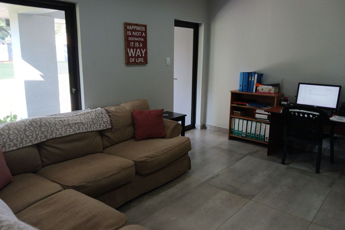 A living room area featuring large format floor tiles and a sliding glass door providing access to the exterior.