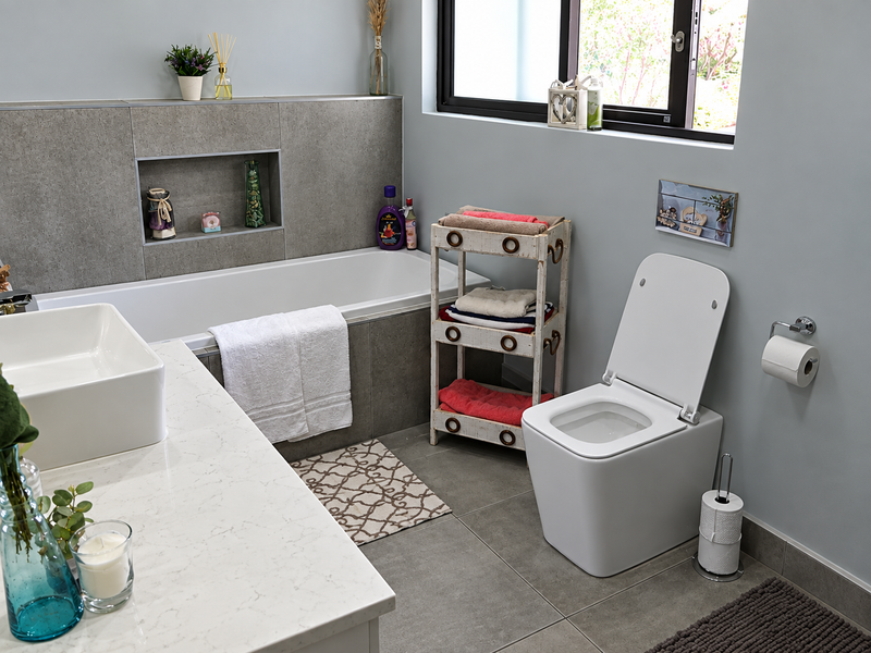 Modern bathroom featuring a built-in bathtub with a recessed niche, a wall-mounted toilet, and a sleek countertop basin on a stone vanity.