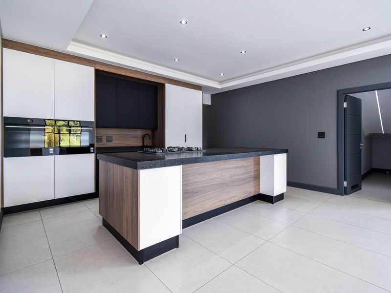 Modern kitchen featuring a central island with a built-in gas hob, sleek cabinetry, integrated oven, and high-quality tiled flooring.