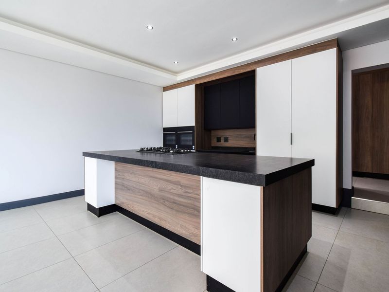 Modern kitchen featuring a central island with a built-in gas hob, sleek cabinetry, and integrated appliances in a clean, contemporary design.