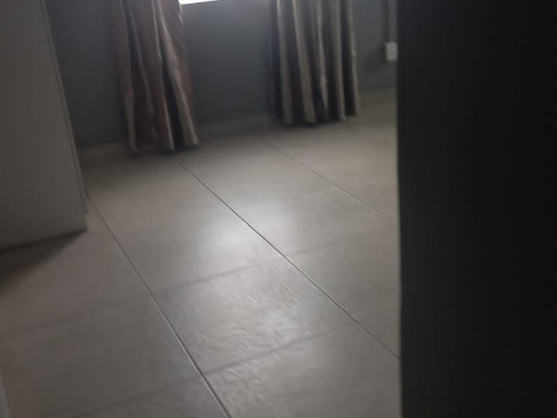 An empty bedroom featuring neutral tiled flooring and a window, providing a blank canvas for personalization.