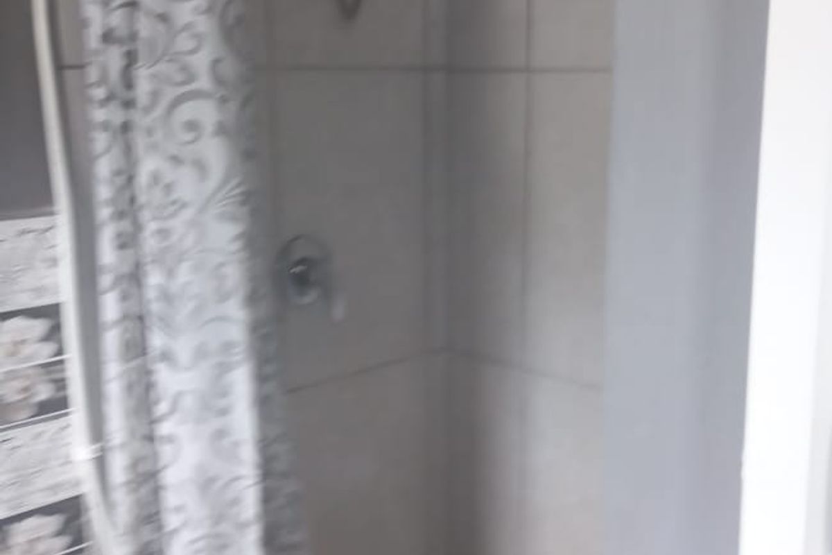 A functional bathroom shower area featuring wall tiling and a standard shower head fixture.