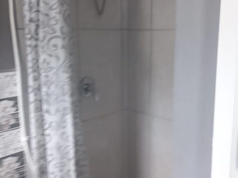 A functional bathroom shower area featuring wall tiling and a standard shower head fixture.