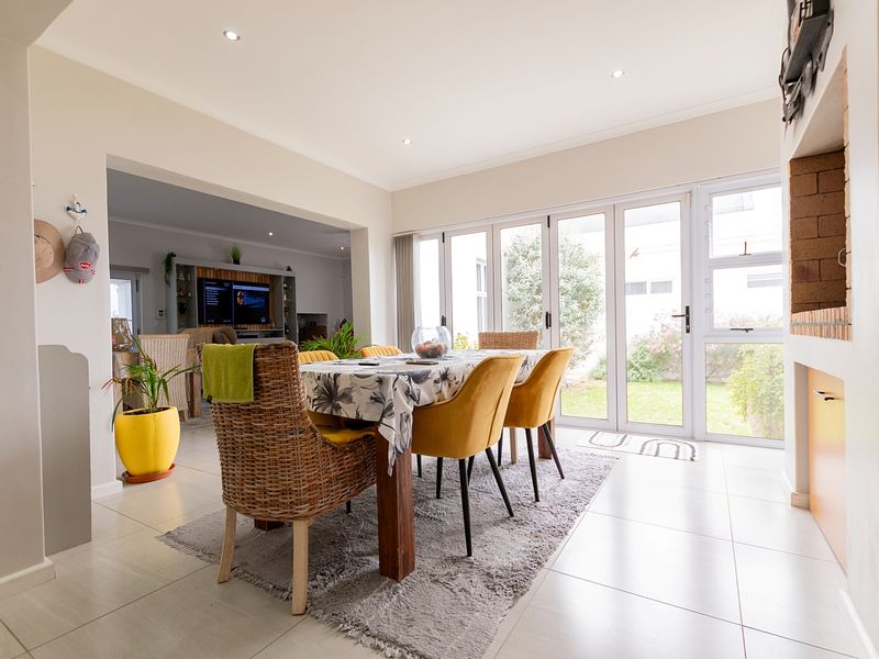 Bright open-plan living and dining area featuring tiled floors, recessed lighting, a built-in fireplace, and bi-fold doors opening to the garden.