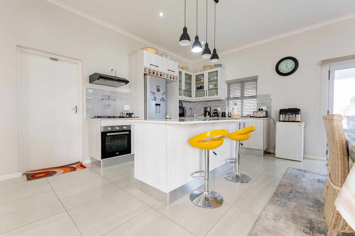 Modern kitchen featuring a central island, light-toned cabinetry, subway tile backsplash, built-in oven, and gas hob, complemented by sleek tiled flooring.