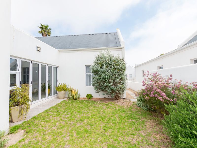 A private rear courtyard featuring a small lawn, paved pathway, and bi-fold glass doors providing seamless access to the interior living space.