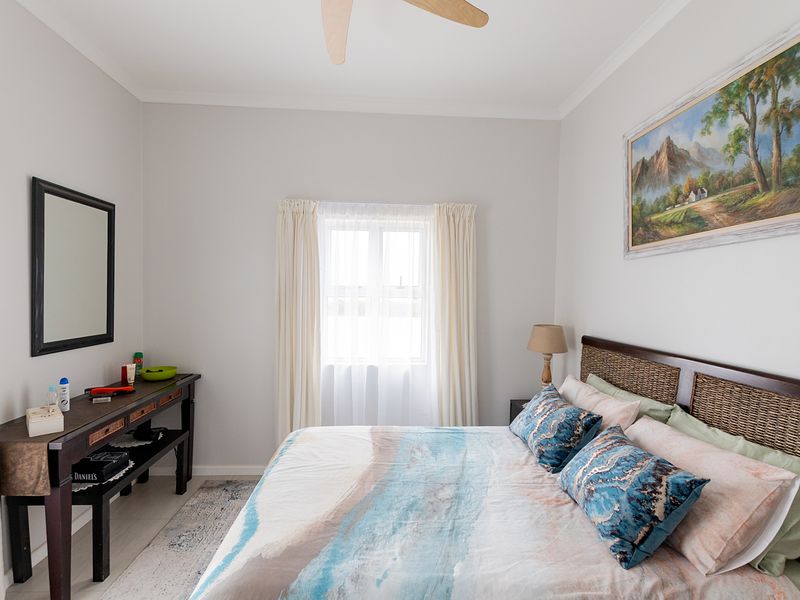A well-maintained bedroom featuring neutral wall tones, tiled flooring, and a ceiling fan, providing a comfortable and functional living space.