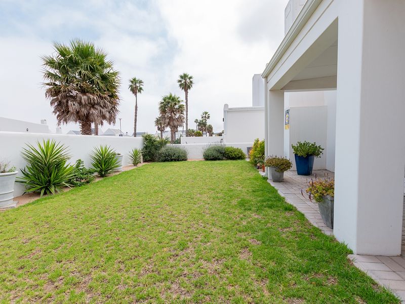 A well-maintained rear garden featuring a paved patio area, a neat lawn, and a secure boundary wall.