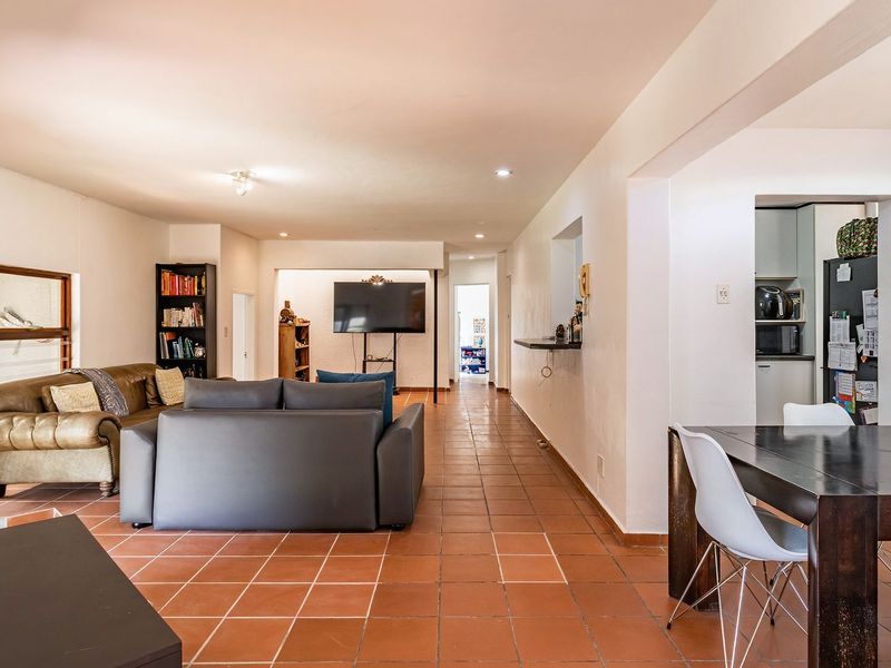 Spacious open-plan living and dining area featuring terracotta floor tiles, recessed lighting, and a convenient breakfast bar connecting to the kitchen.
