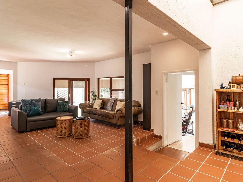 Spacious living area featuring terracotta floor tiles, recessed lighting, and a prominent structural steel column, with direct access to the front entrance.