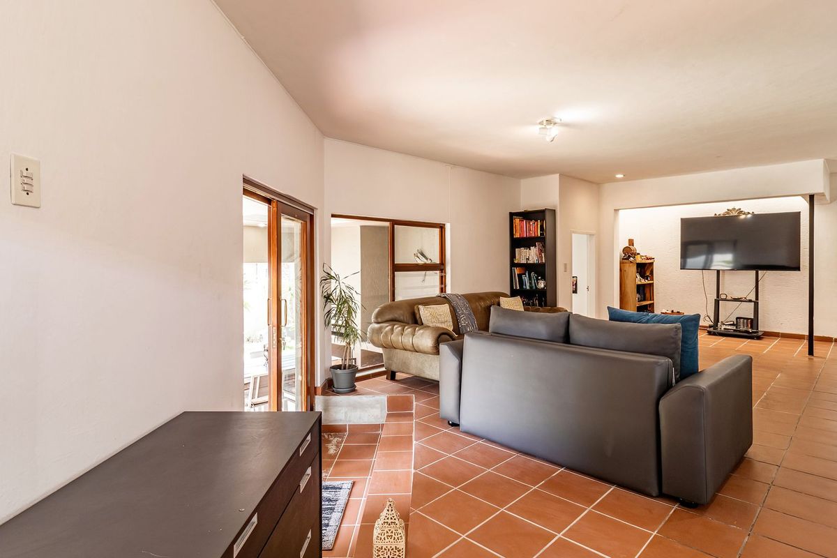 Spacious living area featuring terracotta floor tiles, recessed lighting, and large sliding glass doors providing access to the outdoor space.