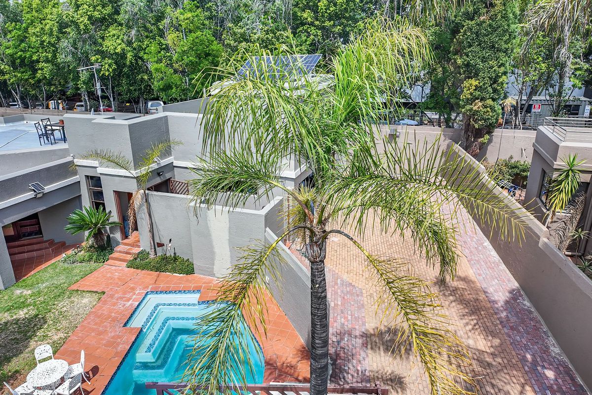 Aerial view of the property featuring a swimming pool, paved courtyard area, and solar panels installed on the roof.