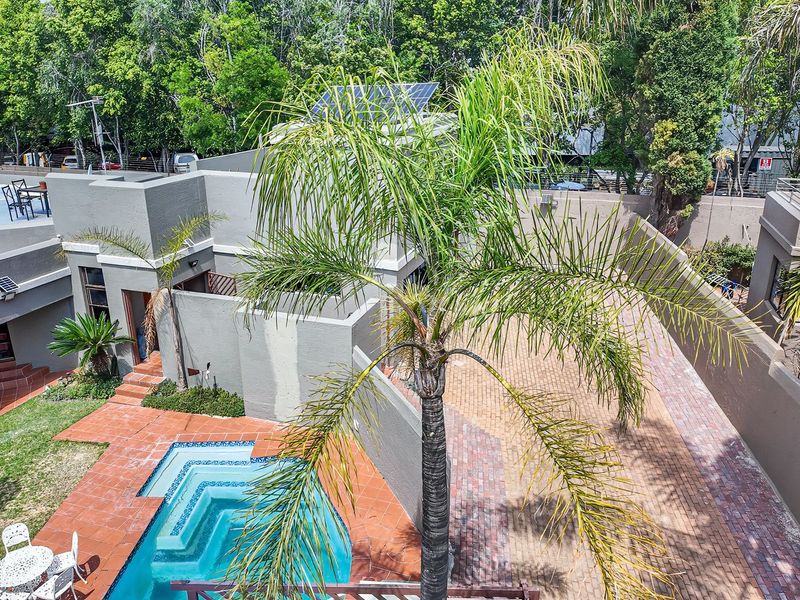 Aerial view of the property featuring a swimming pool, paved courtyard area, and solar panels installed on the roof.