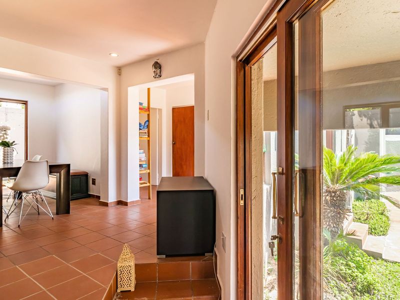 Open plan living area featuring terracotta floor tiles and large sliding glass doors providing direct access to the outdoor pool area.